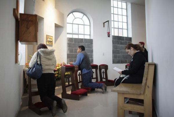 Cat&oacute;licos rezam perto de janelas cobertas parcialmente com blocos de cimento no interior da igreja de Santa Teresa de &Aacute;vila em Monterrey(Imagem:Reprodu&ccedil;&atilde;o)