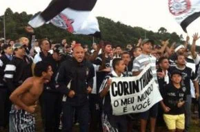 Corintianos esperam pela passagem do ônibus na rodovia