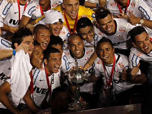 Emerson (ao centro) e os demais jogadores do Corinthians posam ao lado da Ta&ccedil;a Libertadores(Imagem:Reprodu&ccedil;&atilde;o)