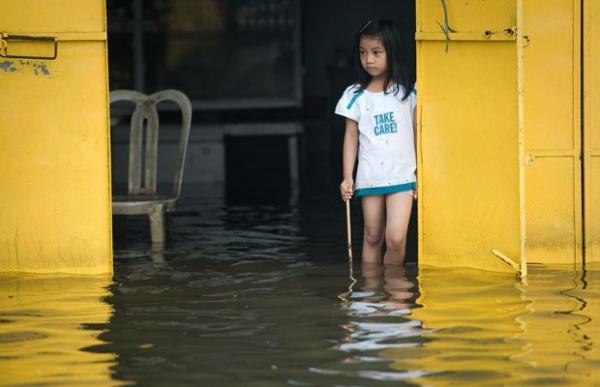 Menina em restaurante alagado em Manila, capital das Filipinas (Imagem:Nicolas Asfouri/AFP)